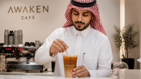 Barista in Riyadh preparing an iced beverage with a paper straw