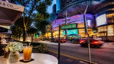 Orchard Road shopping district in Singapore with a cafe table featuring paper straws