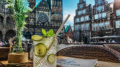Refreshing beverage with a paper straw at a historic café in Bremen's medieval market square