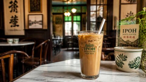 Iced Ipoh white coffee with a paper straw on a marble table in a restored heritage shophouse café