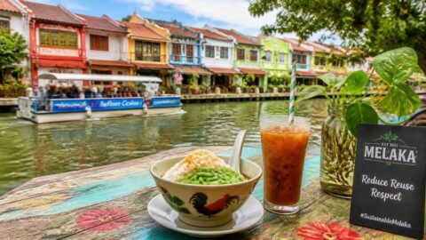 Cold beverage with a paper straw and traditional cendol along the historic Malacca River