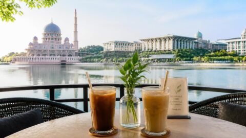 Iced beverages with paper straws at a Putrajaya lakeside café with the Putra Mosque in the background