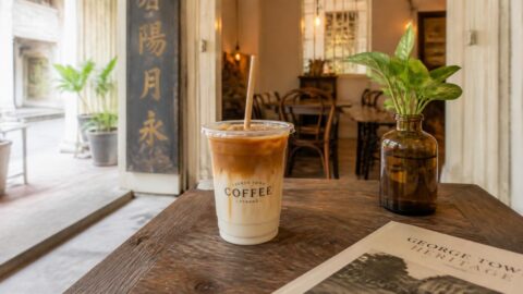 Modern specialty coffee with a paper straw inside a restored George Town heritage café